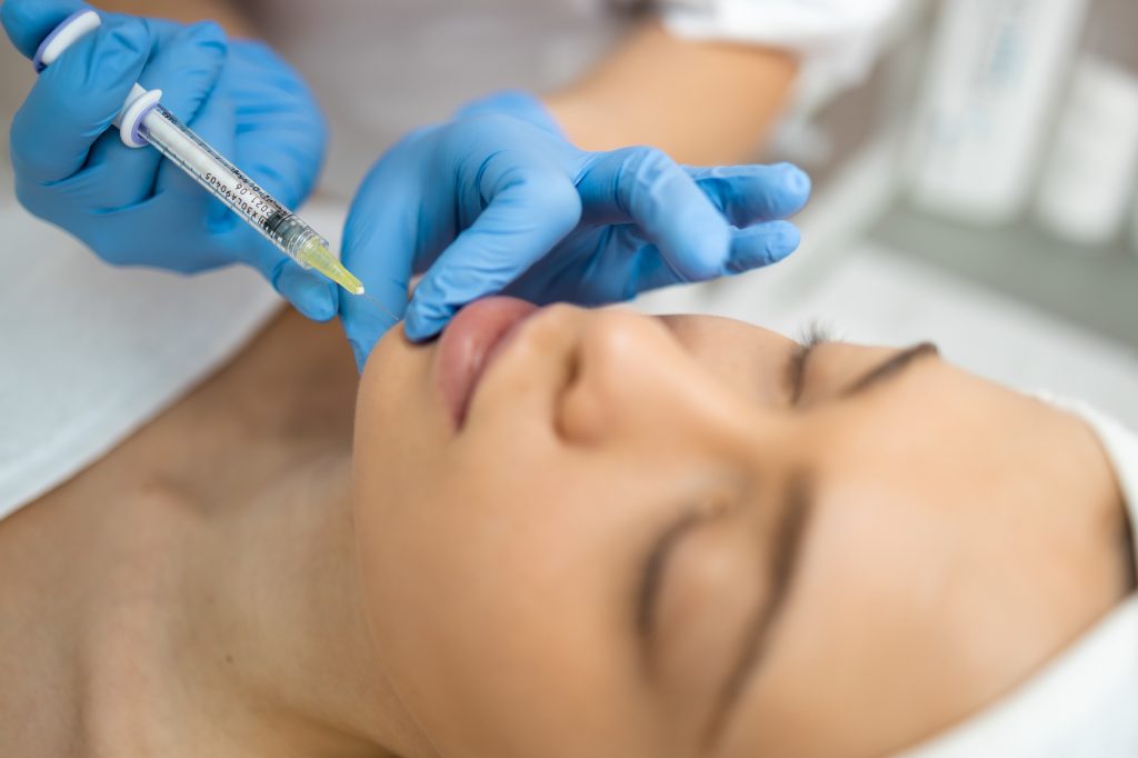 Close up of female face receiving a chin injection of dermal filler in Warrenton, VA
